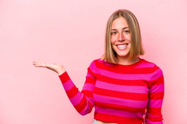 Pembe arka planda izole edilmiş genç beyaz kadın bir avuç içinde fotokopi alanı ve belinde bir el daha gösteriyor..