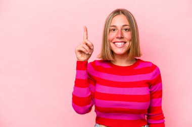 Pembe arka planda izole edilmiş beyaz bir kadın bir numarayı parmağıyla gösteriyor..