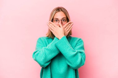 Pembe arka planda izole edilmiş beyaz bir kadın elleriyle ağzını kapatırken şok oldu..