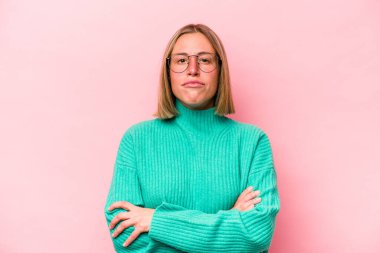 Pembe arka planda izole edilmiş genç beyaz kadın şüpheli, belirsiz, seni muayene ediyor..