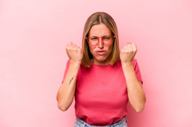 Pembe arka planda izole edilmiş genç beyaz kadın gergin elleriyle çığlık atıyor..