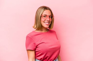 Pembe arka planda izole edilmiş beyaz bir kadın. Kendine güveni tam. Kalçalarını tutuyor..