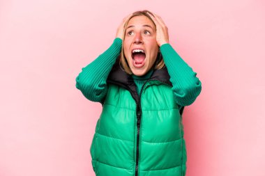 Pembe arka planda izole edilmiş genç, beyaz bir kadın. Kulakları kulaklarıyla kapatıyor. Çok fazla ses duymamaya çalışıyor..