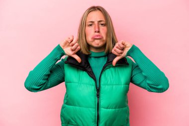 Pembe arka planda izole edilmiş genç beyaz bir kadın hoş olmayan bir jest gösteriyor. Anlaşmazlık konsepti.