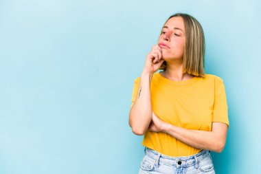 Mavi arka planda soyutlanmış beyaz bir kadın şüpheli ve şüpheci bir ifadeyle yana bakıyor..