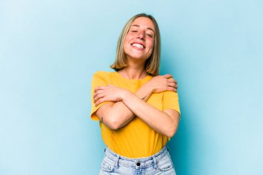 Kafkasyalı genç kadın mavi arka planda izole edilmiş, güler yüzlü ve mutlu..