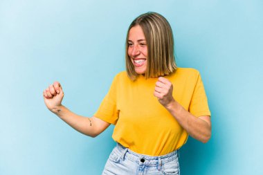 Genç beyaz kadın mavi arka planda izole edilmiş dans ediyor ve eğleniyor..