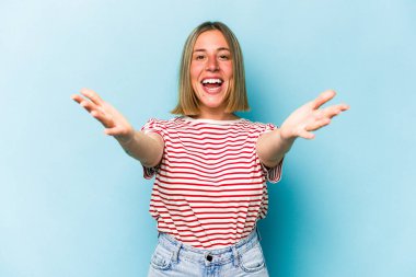 Mavi arka planda izole edilmiş genç beyaz kadın kameraya sarıldığı için kendinden emin..