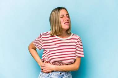 Mavi arka planda karaciğer ağrısı çeken, karnı ağrıyan beyaz bir kadın..