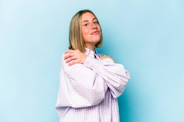 Kafkasyalı genç kadın mavi arka planda izole edilmiş, güler yüzlü ve mutlu..