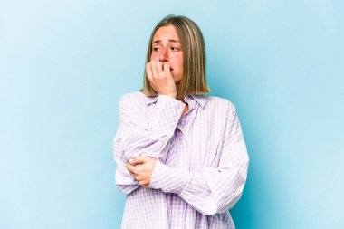 Mavi arka planda izole edilmiş, tırnak yiyen, gergin ve endişeli bir beyaz kadın..