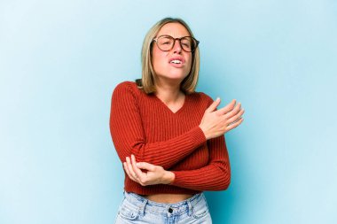 Beyaz bir kadın mavi arka planda izole edilmiş dirsek masajı yapıyor, kötü bir hareketin ardından acı çekiyor..