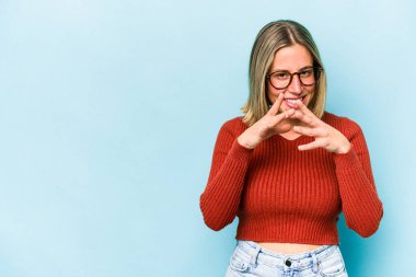 Kafkasyalı genç bir kadın mavi arka planda izole edilmiş bir plan kuruyor, bir fikir kuruyor..