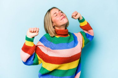 Mavi arka planda izole edilmiş genç beyaz kadın kollarını uzatıyordu, rahat bir pozisyondaydı..