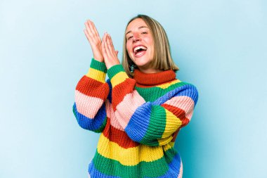 Mavi arka planda izole edilmiş genç beyaz kadın enerjik ve rahat hissediyor, ellerini ovuşturuyor..