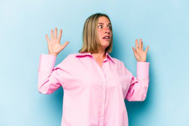 Genç beyaz kadın, mavi arka planda izole edilmiş. Yakın bir tehlike nedeniyle şoka uğruyor.