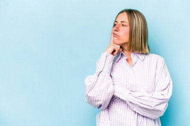 Mavi arka planda soyutlanmış beyaz bir kadın şüpheli ve şüpheci bir ifadeyle yana bakıyor..