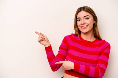 Beyaz arka planda izole edilmiş beyaz tenli genç bir kadın işaret parmağıyla işaret ederek heyecanlanıyor..
