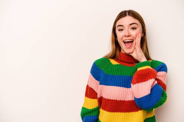 Beyaz arka planda izole genç beyaz kadın yüksek sesle bağırıyor, gözleri açık ve elleri gergin tutuyor..