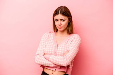 Pembe arka planda soyutlanmış beyaz bir kadın hoşnutsuzca kaşlarını çatmış, kollarını kavuşturmuş..