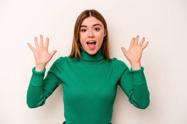 Beyaz arka planda izole genç beyaz kadın zaferi ya da başarıyı kutluyor, şaşırıyor ve şok oluyor..