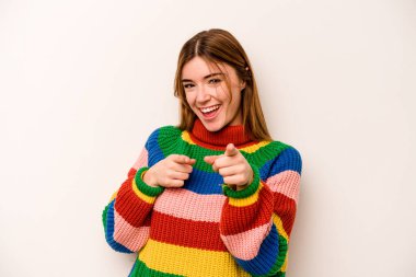 Beyaz arka planda izole edilmiş genç beyaz kadın parmaklarıyla ön tarafı işaret ediyor..