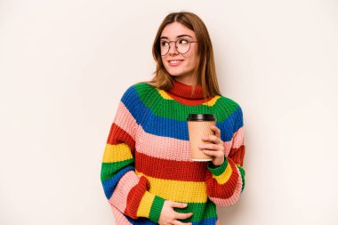 Beyaz arka planda izole edilmiş kahve taşıyan beyaz bir kadın gülümsüyor, neşeli ve keyifli görünüyor..