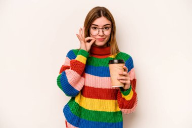 Beyaz arka planda izole edilmiş kahve taşıyan beyaz tenli genç bir kadın dudaklarında bir sır saklıyor..