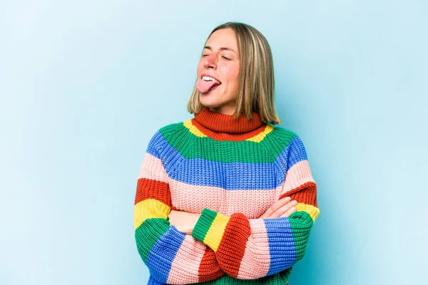 Mavi arka planda izole edilmiş beyaz bir kadın. Komik ve dost canlısı bir dil uzatıyor..