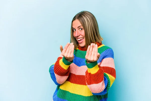 Mavi arka planda izole edilmiş genç beyaz kadın sanki seni davet ediyormuş gibi seni işaret ediyor..