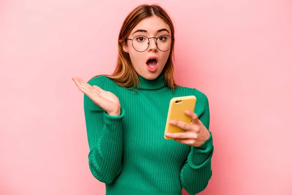 Молодая Белая Женщина Мобильным Телефоном Розовом Фоне Удивлена Шокирована — стоковое фото