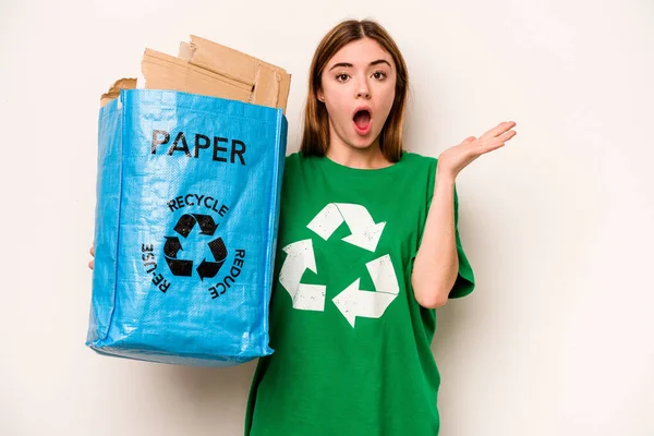 Młoda Kobieta Trzyma Worek Papierem Recyklingu Odizolowany Białym Tle Zaskoczony — Zdjęcie stockowe