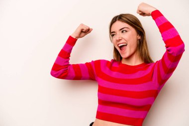 Beyaz arka planda izole genç beyaz kadın zafer kazandıktan sonra yumruğunu kaldırıyor, kazanan konsept..