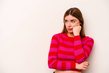 Beyaz arka planda izole edilmiş beyaz tenli genç bir kadın üzgün ve dalgın bir şekilde fotokopi odasına bakıyor..