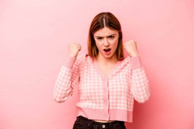 Pembe arka planda izole edilmiş genç beyaz kadın gergin elleriyle çığlık atıyor..