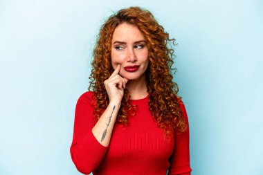 Genç, beyaz, mavi arka planda izole edilmiş bir kadın. Bir strateji planlıyor, bir işin nasıl olacağını düşünüyor..