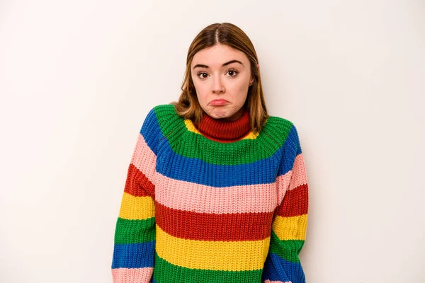 Beyaz arka planda izole edilmiş genç beyaz kadın omuzlarını silker ve gözleri açık kalır..