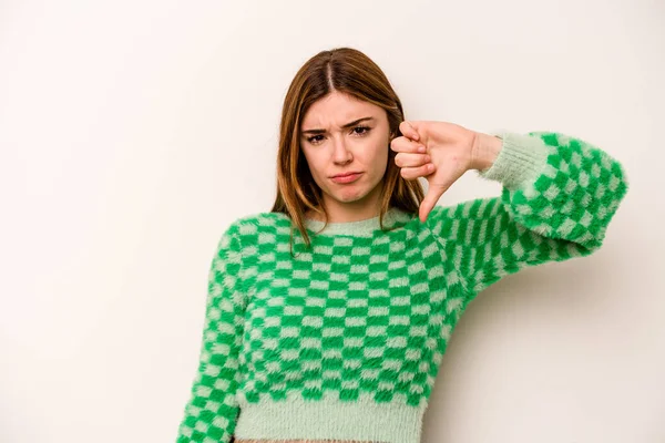 Beyaz arka planda izole edilmiş genç beyaz kadın baş parmağını aşağı gösteriyor ve hoşlanmadığını ifade ediyor..