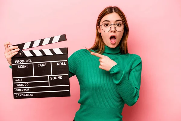 Jonge Kaukasische Vrouw Houden Een Clapperboard Geïsoleerd Roze Achtergrond Wijzend — Stockfoto