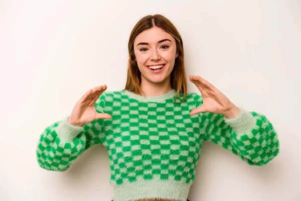 Beyaz arka planda izole edilmiş beyaz bir kadın elinde avuç içi bir şeyle kameraya sunuyor..