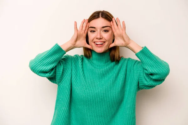 Beyaz arka planda izole genç beyaz kadın hoş bir sürpriz alıyor, heyecanlı ve el kaldırıyor..