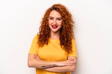 Beyaz arka planda kendini güvende hisseden, kararlılıkla kollarını kavuşturan beyaz tenli genç bir beyaz kadın..