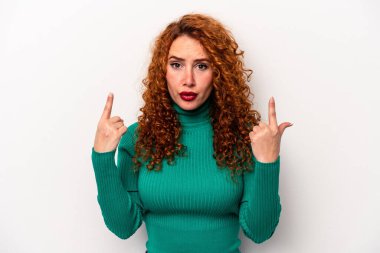 Beyaz arka planda izole edilmiş beyaz tenli genç bir kadın ağzı açık bir şekilde üst tarafı işaret ediyor..