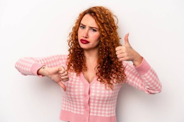 Beyaz arka planda izole edilmiş genç, beyaz tenli bir kadın baş parmağını kaldırıyor ve baş parmağını eğiyor. Zor bir seçim.