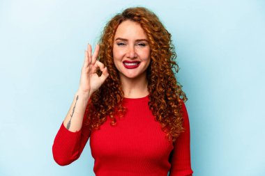 Genç, beyaz, mavi arka planda izole edilmiş, neşeli ve kendinden emin bir kadın..