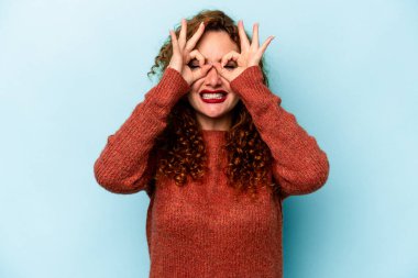 Genç, beyaz, mavi arka planda izole edilmiş bir kadın heyecanlı..