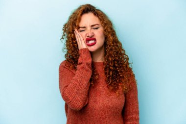 Mavi arka planda soyutlanmış genç, beyaz bir kadın yorgun ve uykulu bir şekilde ellerini başının üstünde tutuyor..