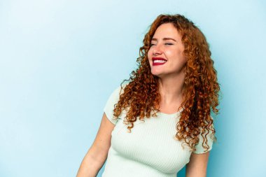 Mavi arka planda izole edilmiş genç, beyaz bir kadın. Rahatlamış ve mutlu bir şekilde gülüyor. Boynunda dişler var..