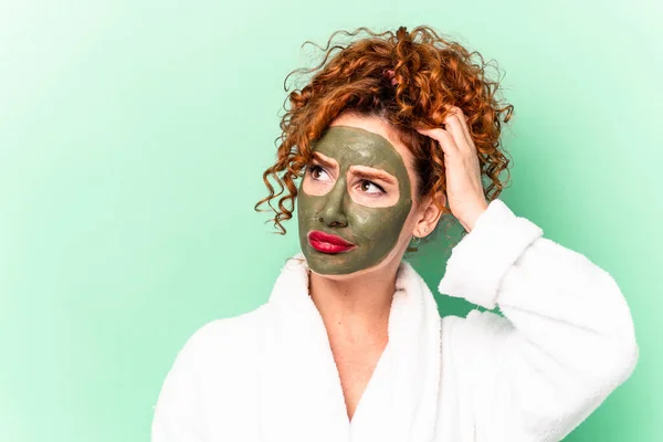 Young red hair woman with a facial aloe vera mask after a bath isolated being shocked, she has remembered important meeting.