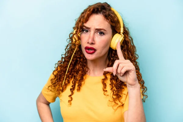 Young Ginger Woman Listening Music Isolated Blue Background Having Idea — Stock Photo, Image